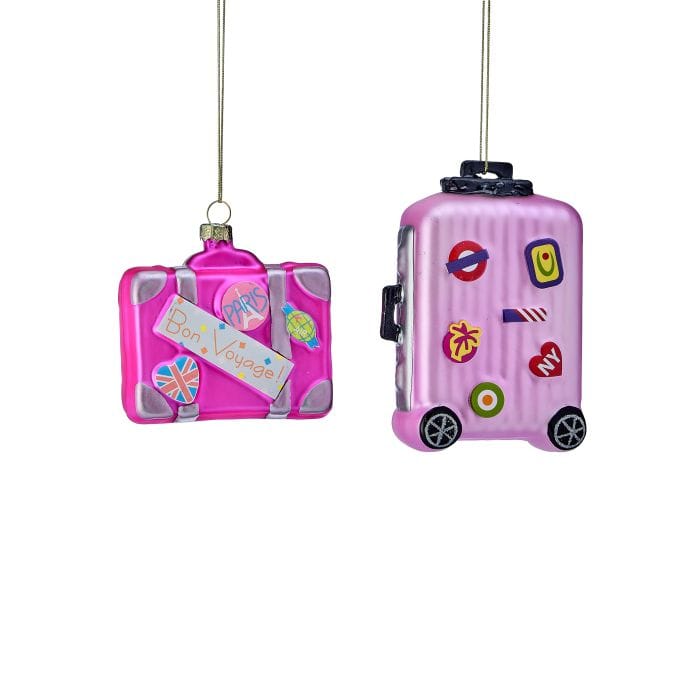 Two pink glass luggage Christmas ornaments with travel stickers, hanging by gold strings