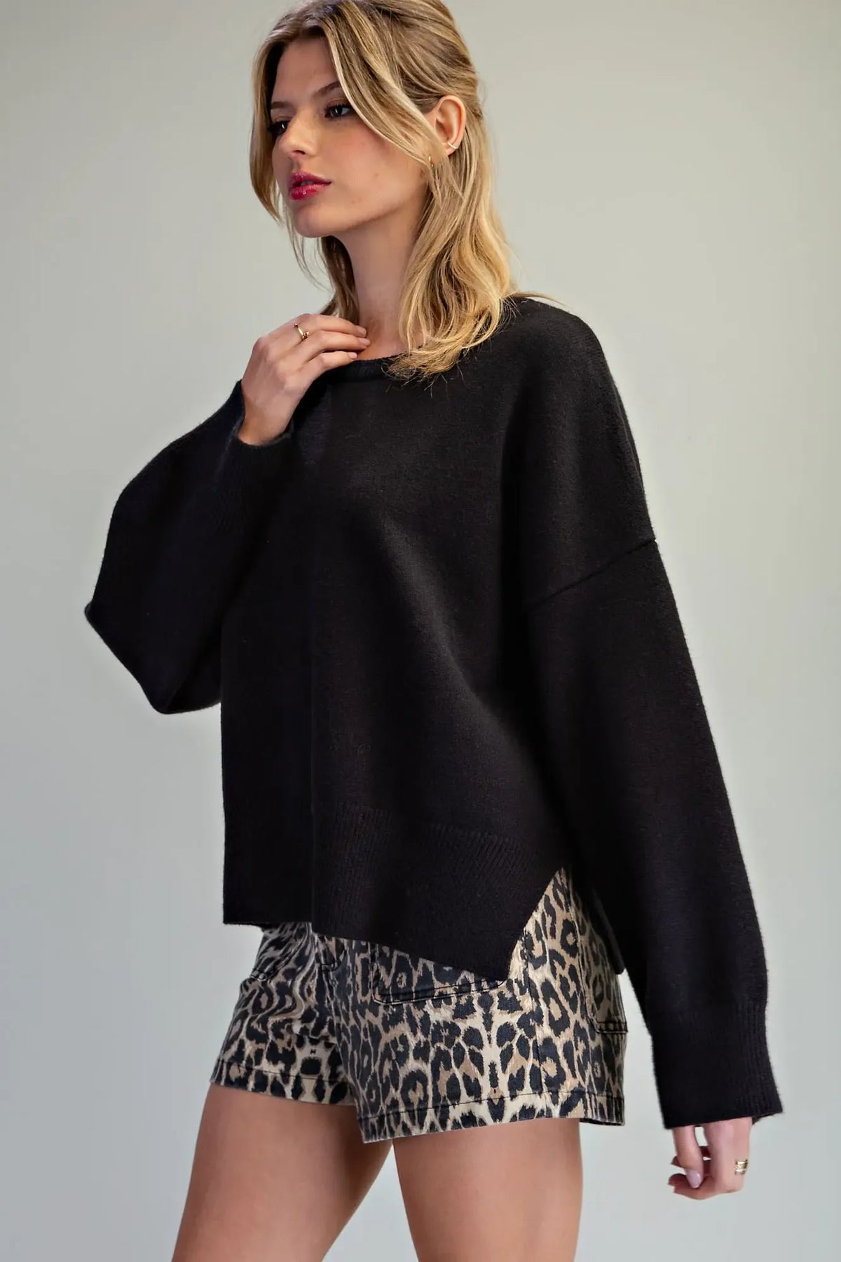 Oversized black crewneck knit sweater with drop shoulders, worn with leopard print shorts