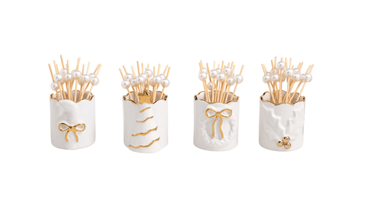 Four white stoneware toothpick holders with gold motifs and pearl-topped wooden toothpicks