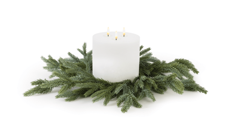 White three-wick pillar candle centered on a green spruce candle ring