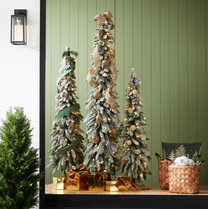 Flocked alpine Christmas trees with warm LED lights, ribbon, and gold ornaments