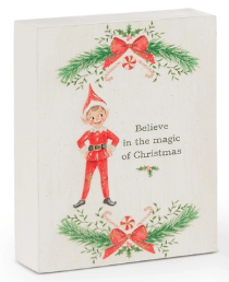 White wood block sign with Christmas elf, pine sprigs, and holiday text