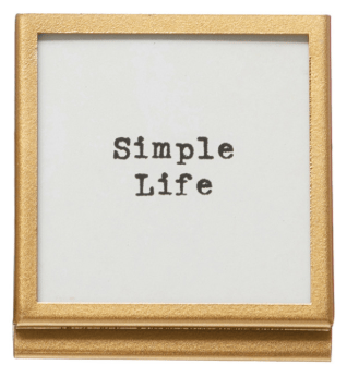 Small gold-framed easel sign with typewriter-style text reading Simple Life