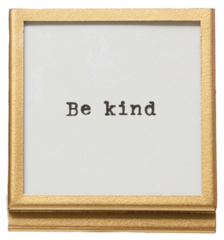Small gold-framed tabletop sign with typewriter-style 'Be kind' text on white