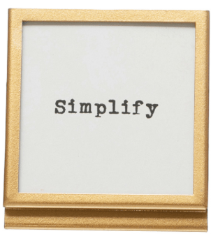 Gold easel frame displaying the word Simplify in typewriter font