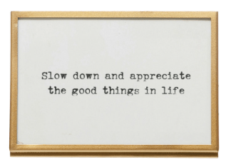 Gold-framed white sign with black typewriter text motivational quote on easel