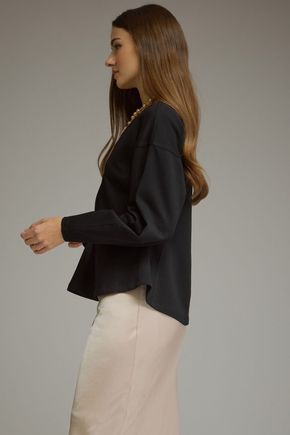 Entro black curved seam long sleeve top paired with cream skirt, side view