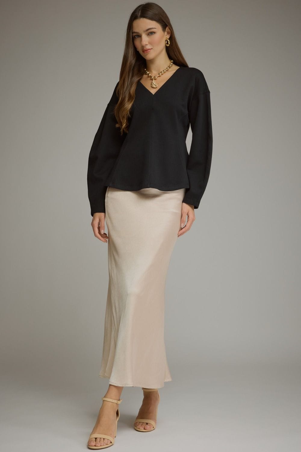 Black long sleeve V-neck curved hem blouse worn with beige satin maxi skirt