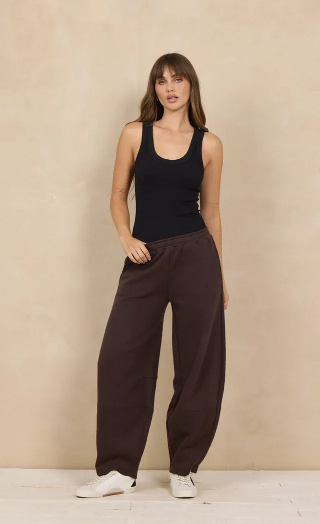 Dark brown wide-leg barrel sweatpants with elastic waist worn with black tank top