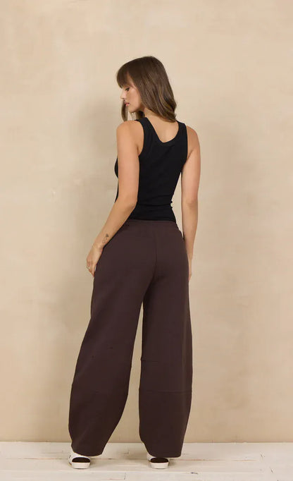 Wide-leg dark brown barrel sweatpants with relaxed fit, worn with black tank top