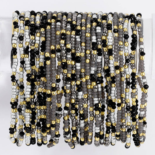 Stacked black, gray, silver, and gold seed bead stretch bracelets on display stand