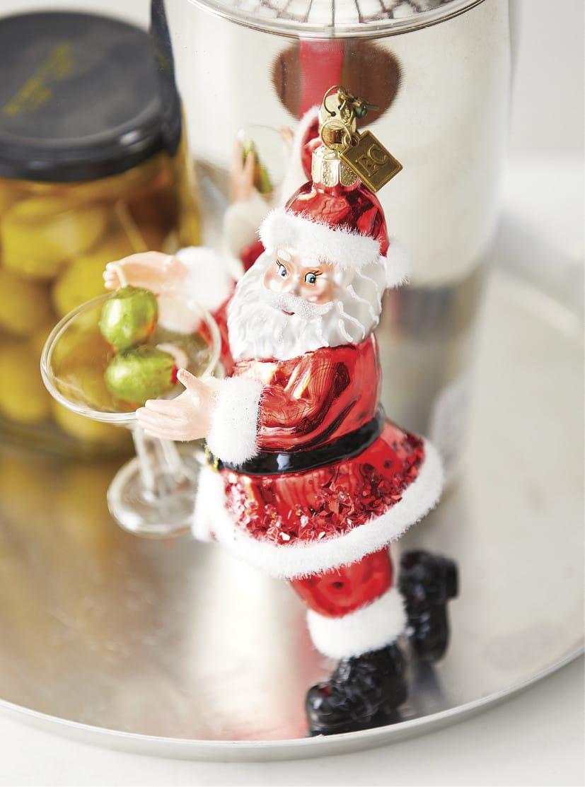 Santa Claus glass ornament holding a martini glass with green olives, festive red suit