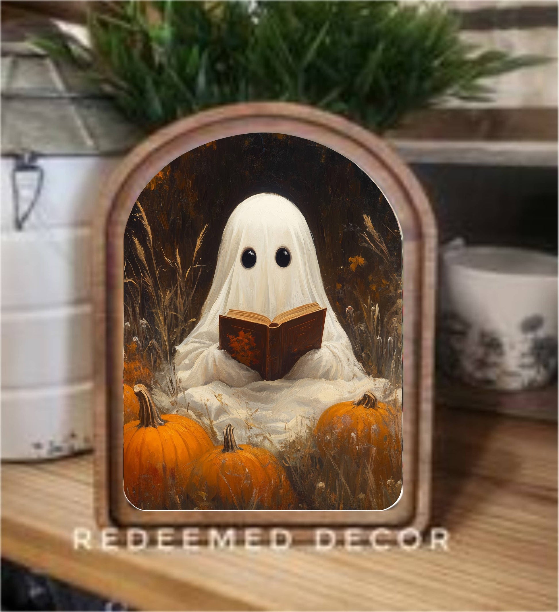 Arched wood-framed canvas art of a ghost reading among orange pumpkins