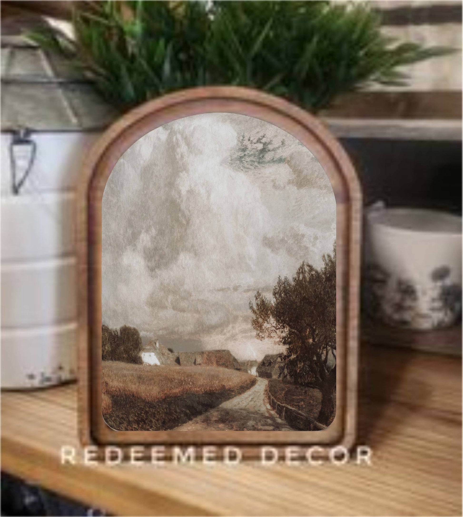 Arch top framed canvas art with moody countryside path and farmhouse scene