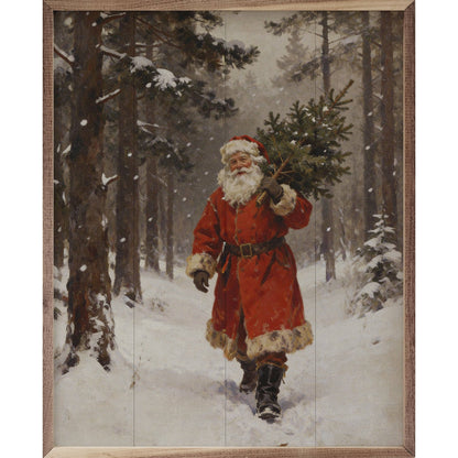 Framed painting of Santa Claus carrying a pine tree through a snowy forest