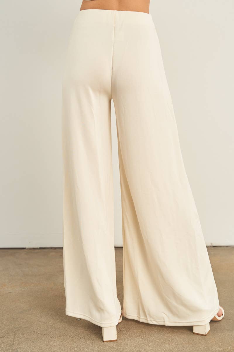Cream wide-leg palazzo pants with high waist, back view, worn with white heels