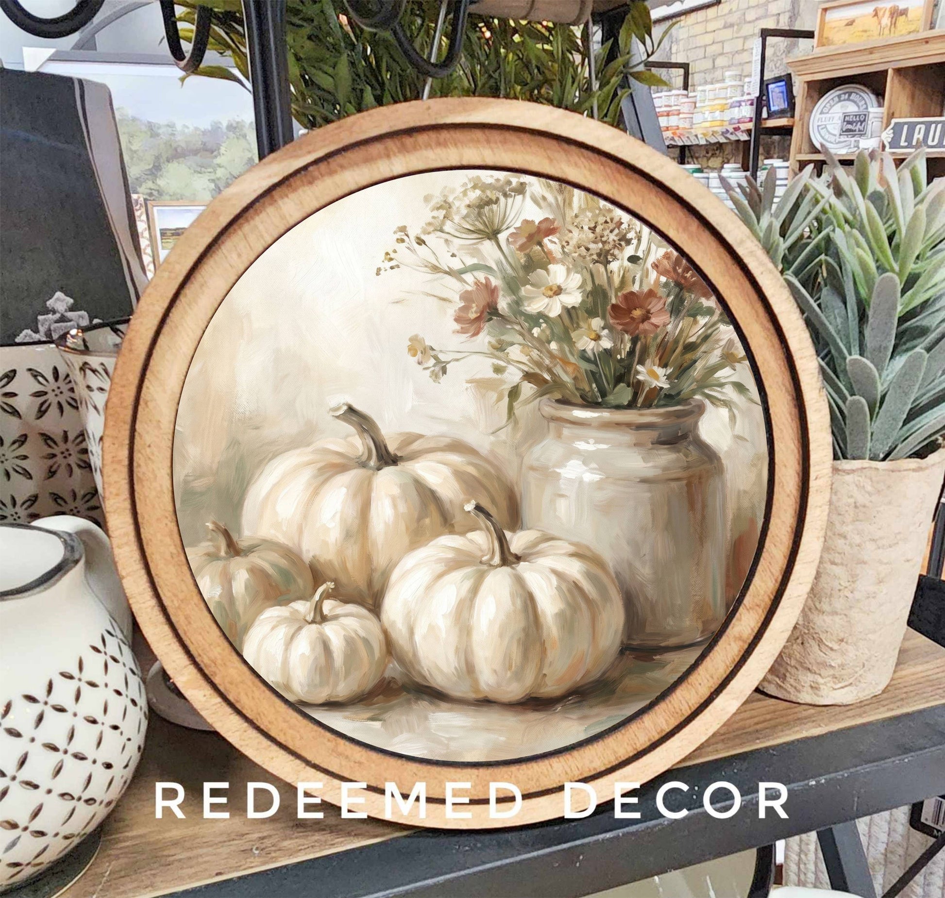 Round wood-framed canvas print of cream pumpkins and wildflowers in neutral tones