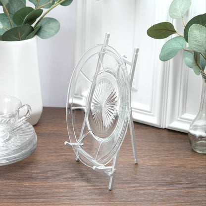 Satin silver metal easel stand displaying a clear glass decorative plate on wood surface.