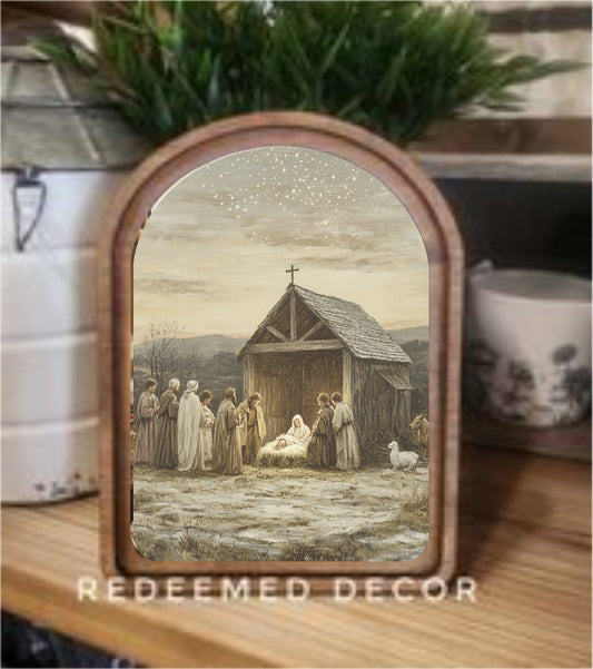 Arch-top wood-framed nativity scene canvas art in warm neutral tones on wooden shelf