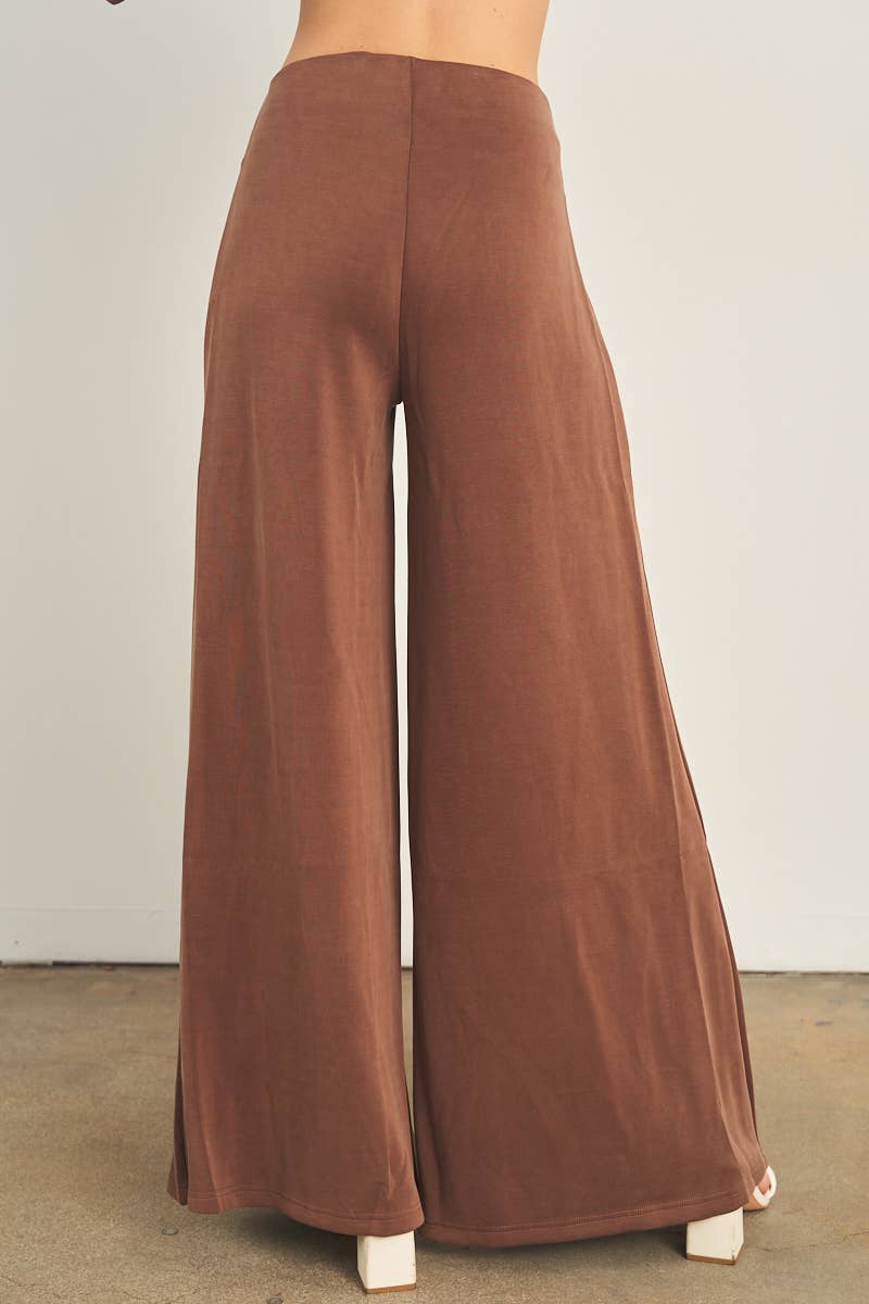 Brown wide-leg palazzo pants with high waistband, worn with white heels
