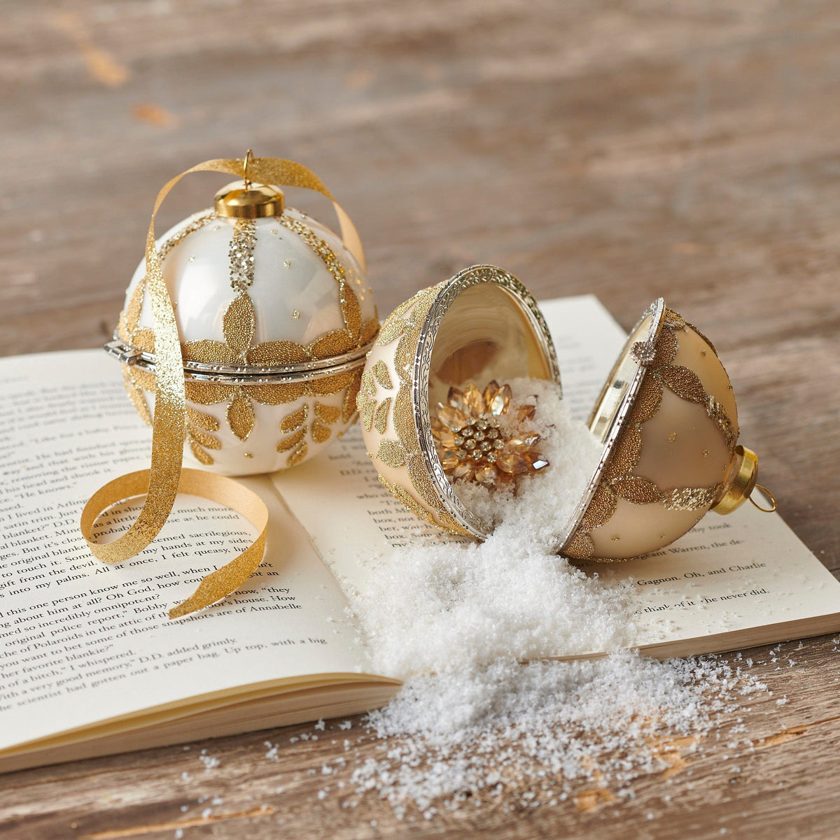 Hinged ornament jewelry boxes open revealing faux snow and amber gemstone flower, on open book