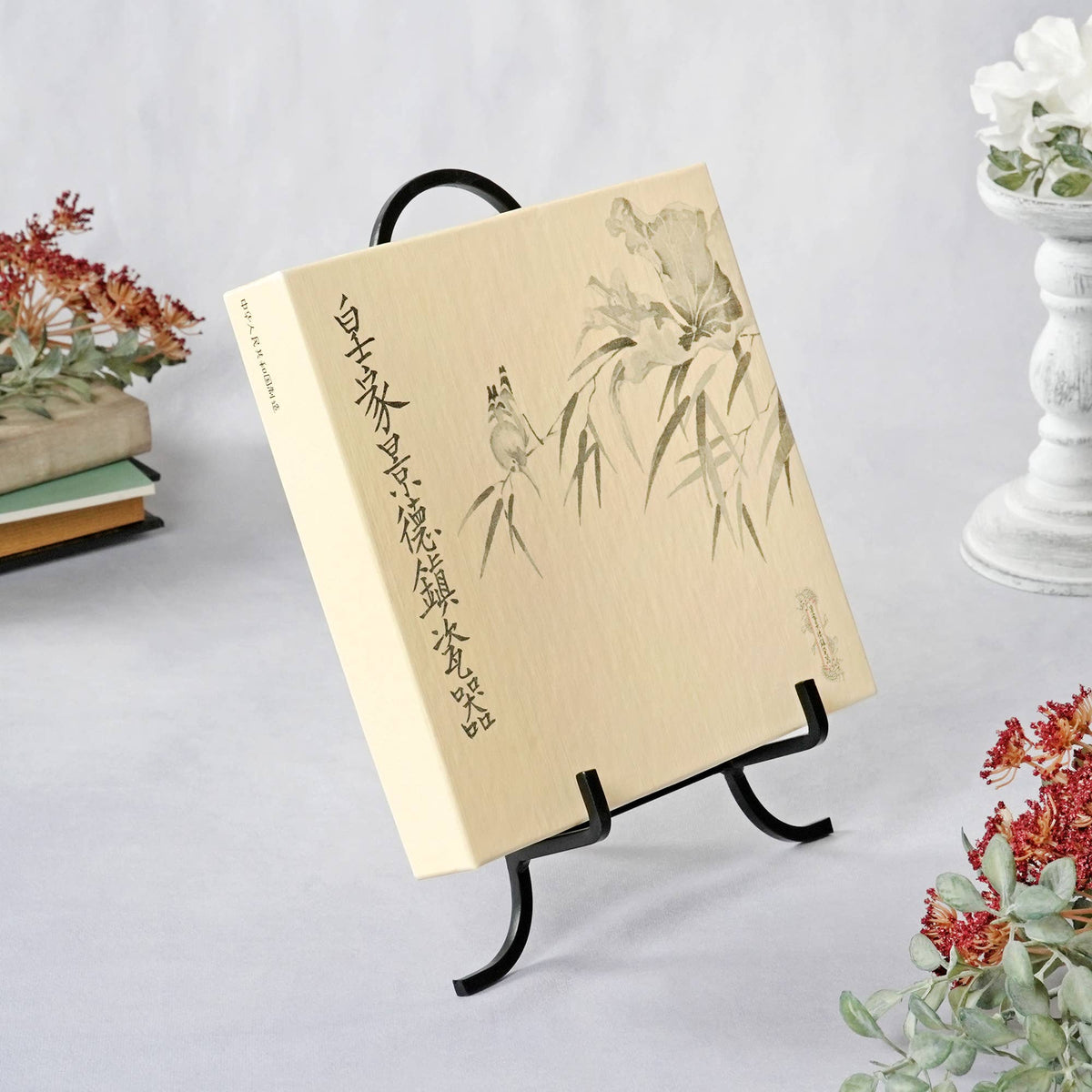 Black wrought iron easel display stand holding a cream Chinese art book