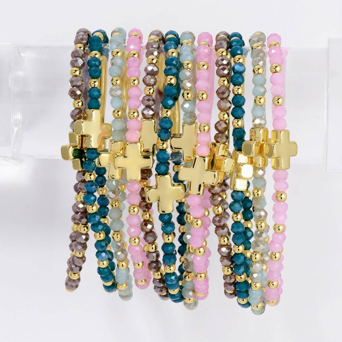Assorted pink, teal, and gray crystal stretch bracelets with gold cross charms