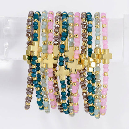 Assorted pink, teal, and gray crystal stretch bracelets with gold cross charms