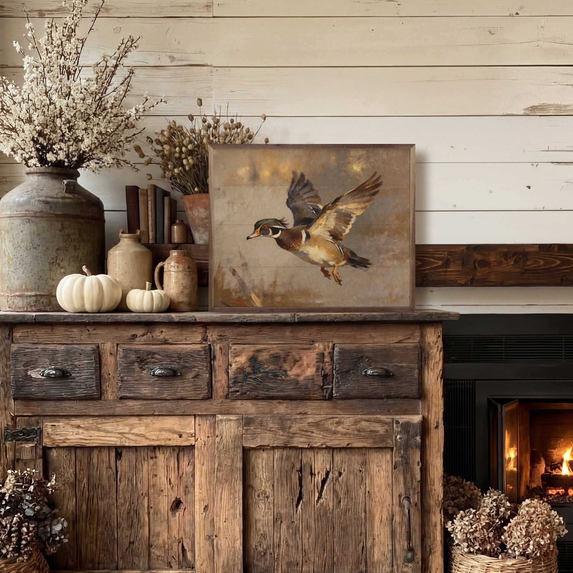 Framed wood duck in flight painting displayed on rustic wooden sideboard near fireplace