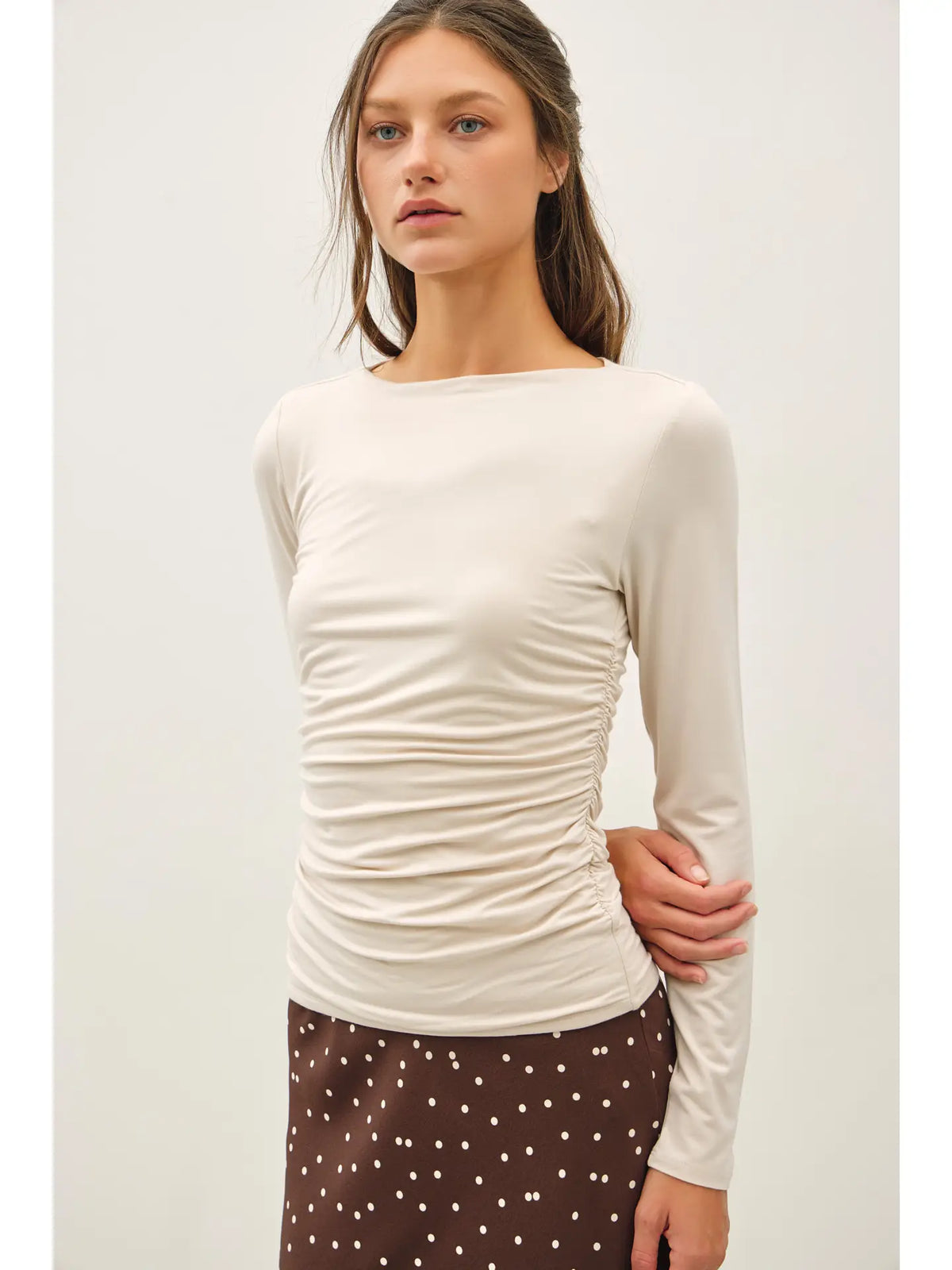 Cream long sleeve boat neck top with side ruching, paired with brown polka dot skirt