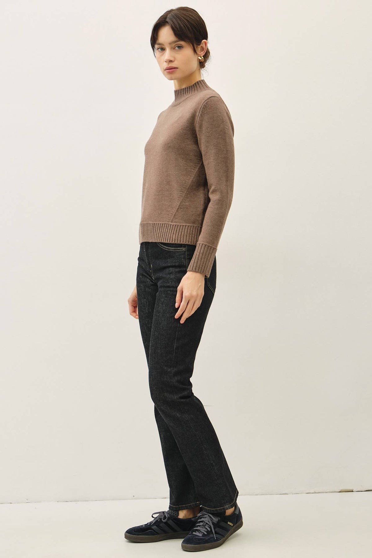Taupe mockneck sweater with ribbed cuffs and hem, paired with dark jeans