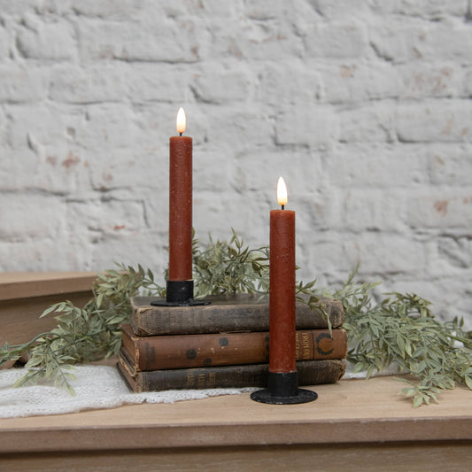 Set of 2 bronze taper candles with black holders on stacked vintage books