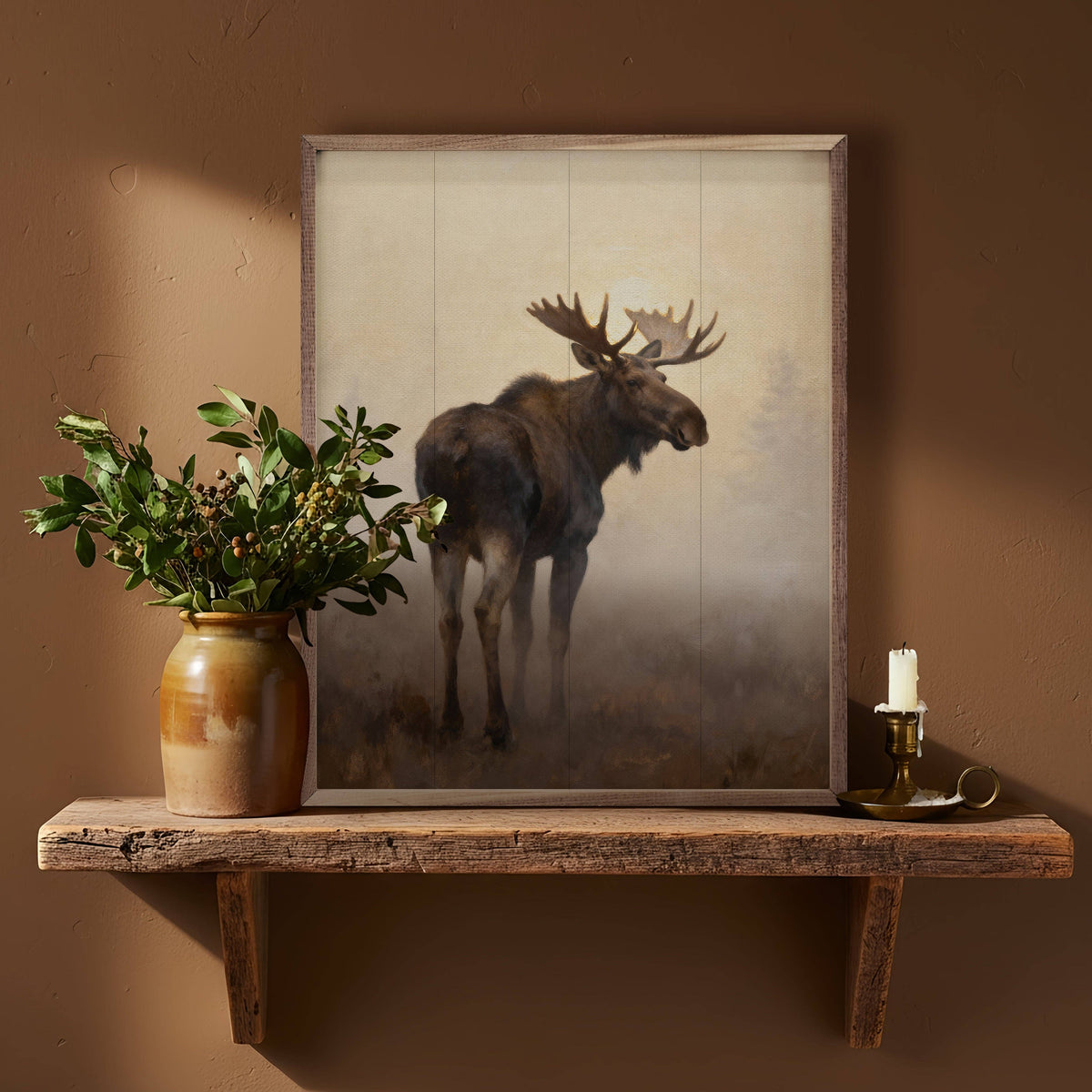 Framed moose painting print in rustic wood frame displayed on natural wood shelf