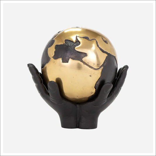 Black metal hands cradling a polished gold brass globe sculpture with world map continents
