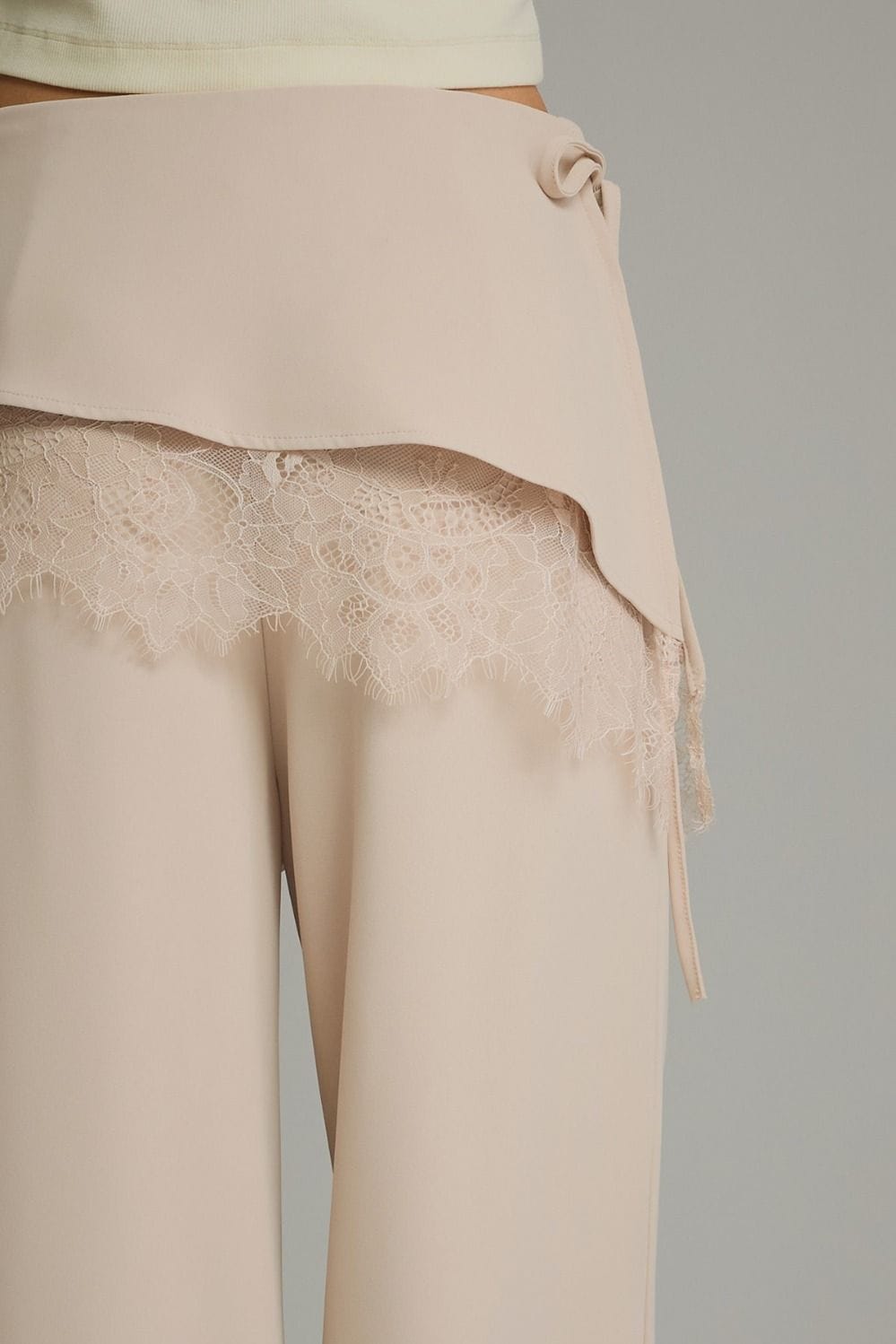 Beige wide-leg pants with wrap overlay and floral lace trim detail