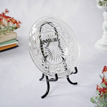 Black wrought iron easel stand displaying a clear pressed glass decorative plate
