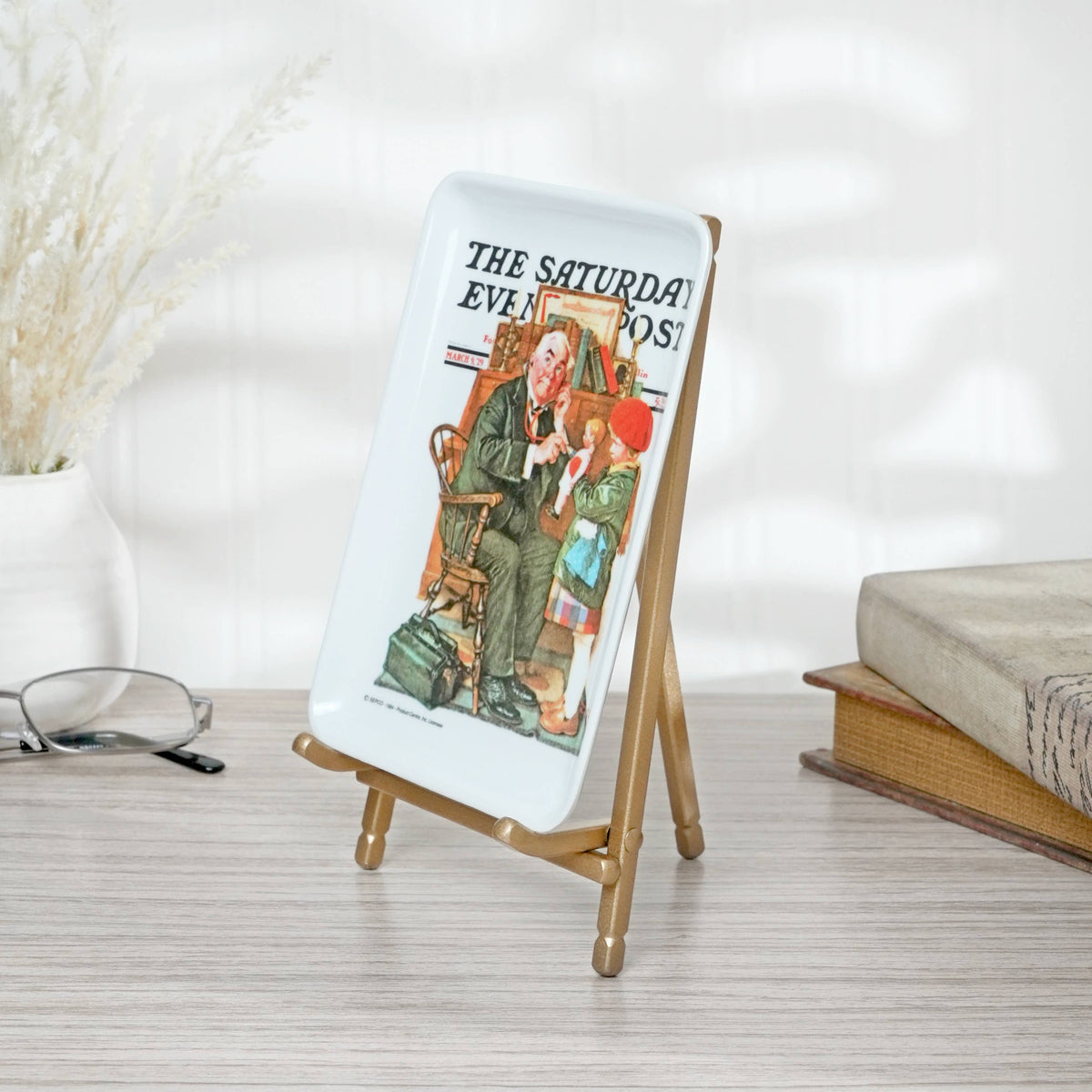 Gold satin metal mini easel displaying a Saturday Evening Post decorative plate on desk