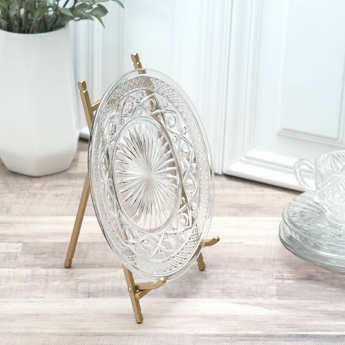 Satin gold metal plate easel displaying clear embossed glass plate on wood surface