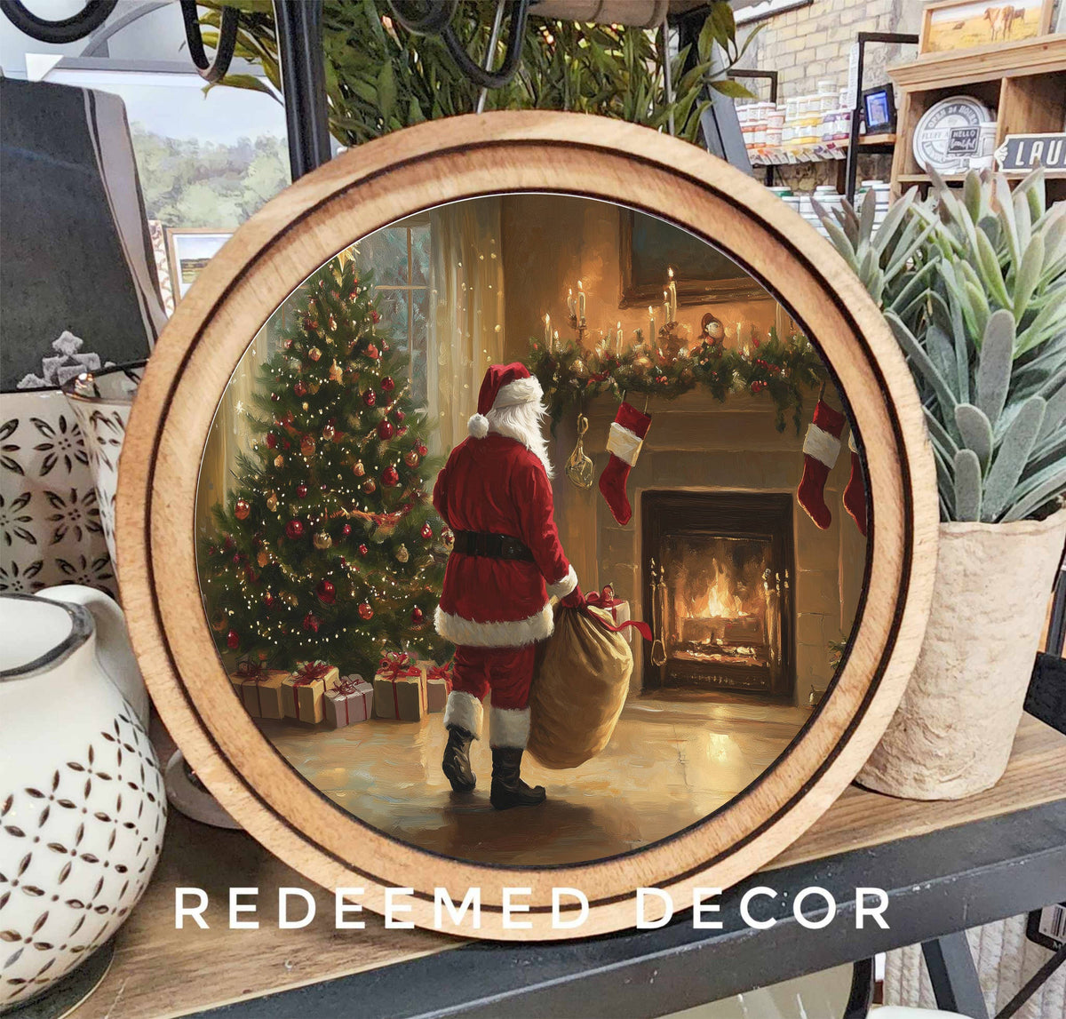 Round wood-framed canvas art of Santa Claus by lit fireplace and decorated Christmas tree