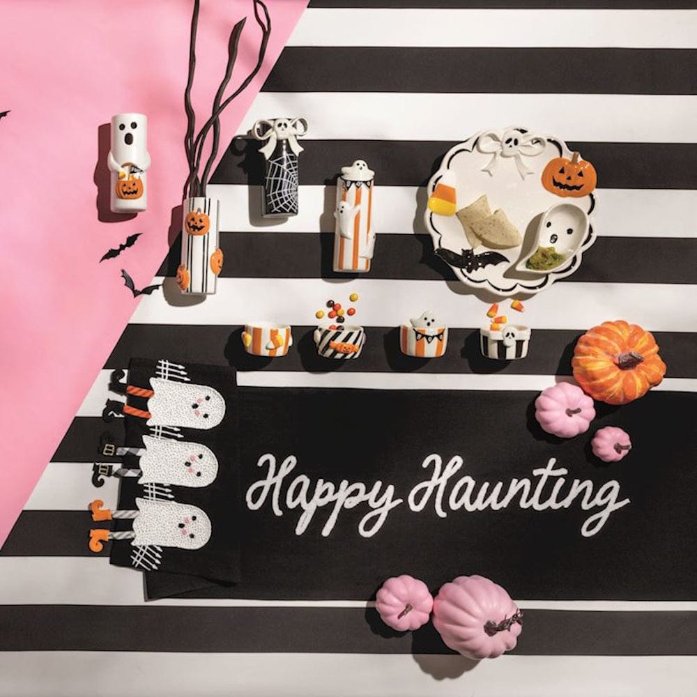 Black Halloween table runner with ghost dangle legs and 'Happy Haunting' script, styled with seasonal decor