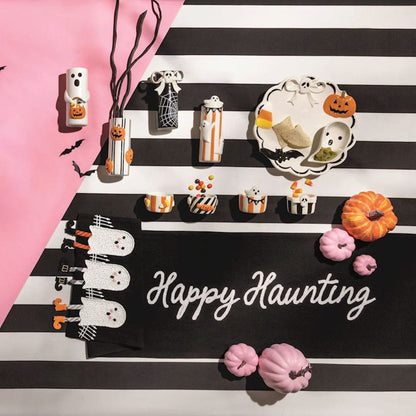 Black Halloween table runner with ghost dangle legs and 'Happy Haunting' script, styled with seasonal decor