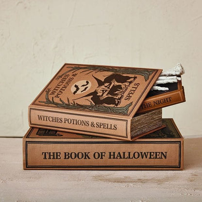 Stack of three Halloween-themed book-shaped storage boxes with spooky decorative covers and skeleton hand detail