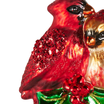 Glass cardinal pair ornament with glitter detailing perched on green holly with red berries