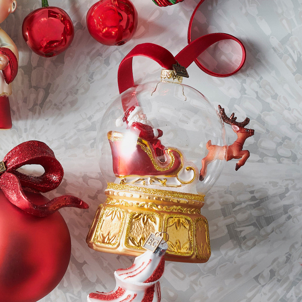 Clear glass globe ornament with Santa sleigh and reindeer scene on ornate gold base