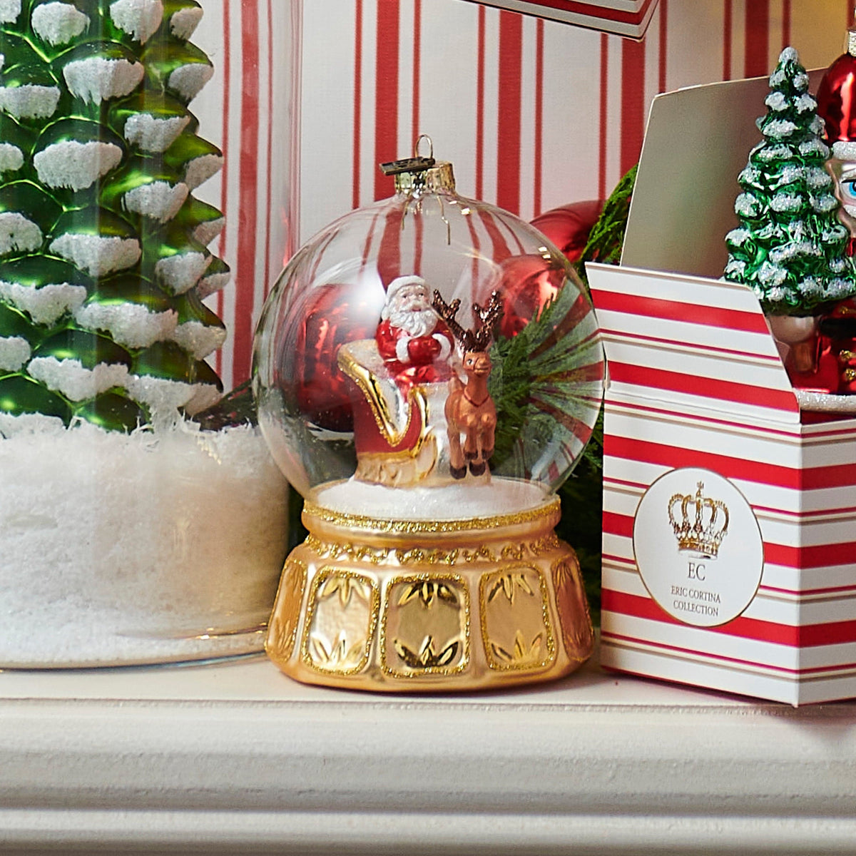Clear glass globe ornament with Santa sleigh scene inside, gold decorative base