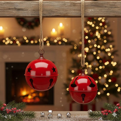 Two large red metal jingle bells with star cutouts hanging from rope in holiday setting