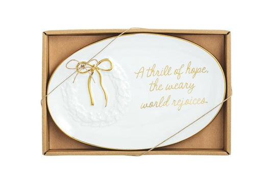 Oval white ceramic plate with gold trim and script reading 'A thrill of hope, the weary world rejoices,' in kraft gift box