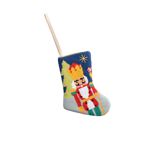 Small needlepoint Christmas stocking featuring a nutcracker soldier and Christmas tree on blue background