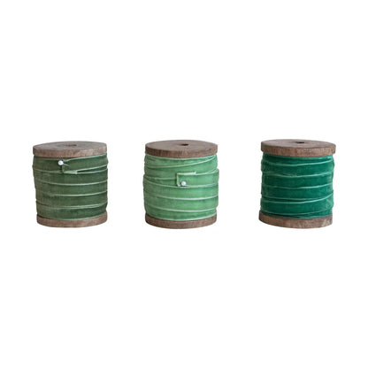 Three wooden spools of green velvet ribbon in light, medium, and dark shades