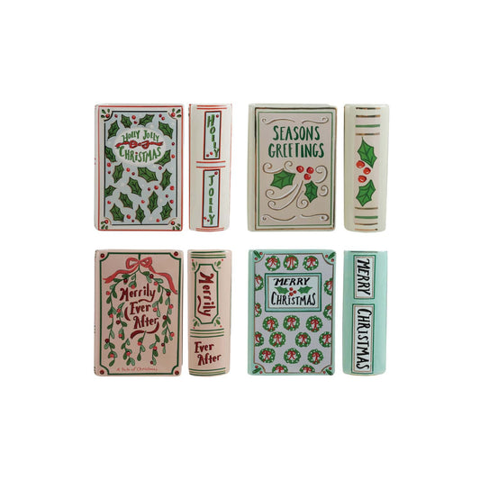 Four ceramic holiday book-shaped vases with festive hand-painted Christmas phrases and holly motifs